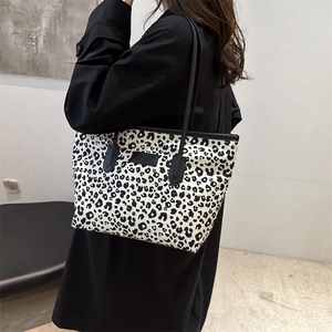 Leopard print tote bag with black leather straps and stylish rectangular emblem