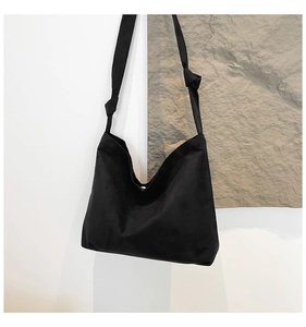 Detail of minimalist black oversized hobo bag showing soft suede texture and knotted shoulder strap