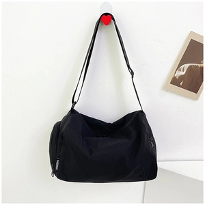 Detail view of black nylon shoulder bag featuring white FASHION tag and side zipper pocket