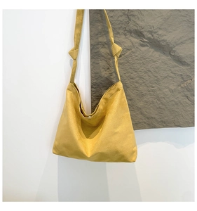 Detail of mustard yellow suede tote bag featuring a knotted shoulder strap and magnetic closure