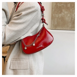 Détail du sac demi-lune rouge avec chaîne perle et cœur et bandoulière nouée élégante