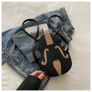 Detail of violin-shaped mini backpack with gold rivets on a white bedding background