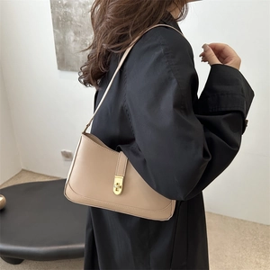 Minimalist beige leather underarm bag with gold rotating clasp shown in a modern interior