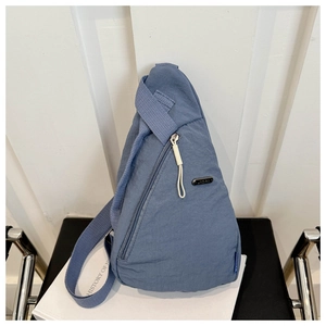 Detailed view of the blue nylon crossbody bag featuring textured fabric and side metal logo