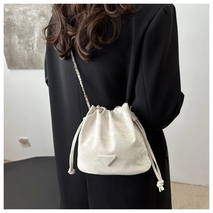 Detail of white drawstring bucket bag with gold chain strap and fashion logo
