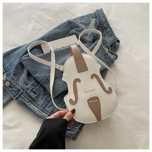 Detailed view of violin-shaped crossbody bag on denim jacket with gold rivet accents