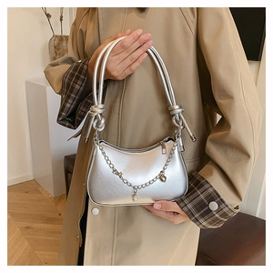 Détail du sac demi-lune argenté avec poignée à nœud, perle et bandoulière chaîne