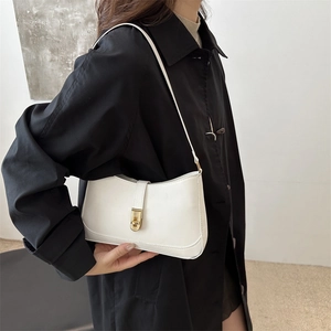 Minimalist white leather shoulder bag with gold twist lock shown on a fashion model