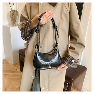 Détail du sac hobo noir avec bandoulière nouée, chaîne perle cœur et fini brillant