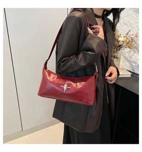 Chic burgundy leather hobo bag with silver cross star detail worn by a model
