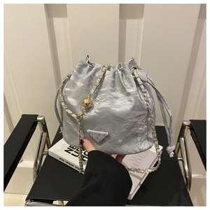 Detail of silver pleated bucket bag with gold chain strap and metallic ball charm