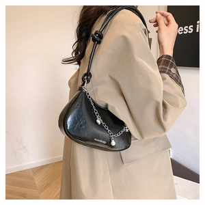 Détail du sac croissant noir avec chaîne argentée et pendentif perle sur un mannequin
