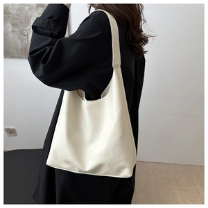 Close-up of creamy white hobo bag with natural crinkled leather texture on a shoulder