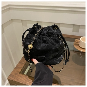 Close-up of black drawstring bucket bag with golden chain and textured fabric finish