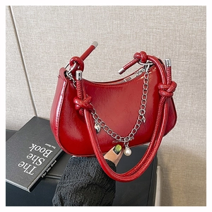 Détail du sac bandoulière en cuir verni rouge avec chaîne argentée et pendentif cœur
