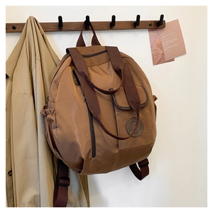 Detail of dark brown waterproof nylon backpack with multi-pocket design and glossy finish