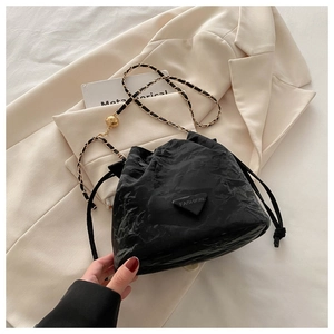 Detail of black drawstring bucket bag with gold-tone chain and metal ball adjustment
