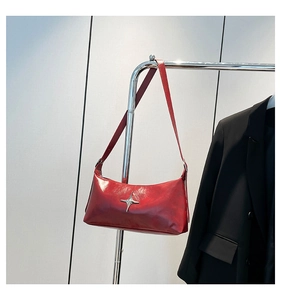 Detail of red glossy leather shoulder bag with a silver metallic star and sleek texture