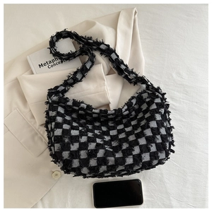 Detail of checkered canvas bag featuring distinctive frayed edges and woven texture