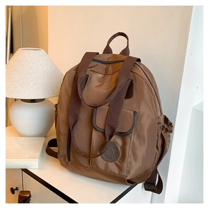 Detail of coffee brown nylon travel backpack featuring front flap pocket and satin finish
