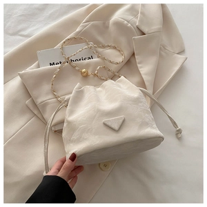 Detail view of white drawstring bucket bag with chain strap and soft pleated texture