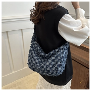 Detail of blue and gray checkered hobo bag with frayed edges and wide shoulder strap