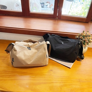 Minimalist nylon crossbody bag in khaki and black on a warm wooden tabletop
