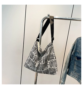 Detail view of a plaid canvas tote bag with an adjustable wide black fabric shoulder strap
