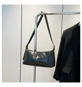 Detail of glossy black leather shoulder bag with silver star hardware on a hanger