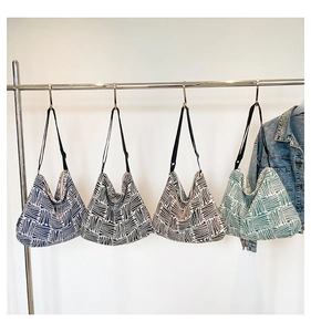 Hanging display showing four large geometric tote bags with adjustable black straps