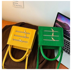 Detail of crocodile pattern leather handbags in yellow and green with zipper accents