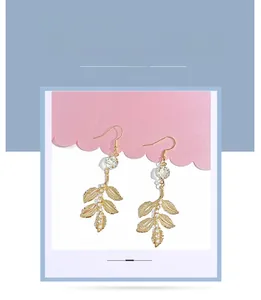 Détail macro de boucles d'oreilles baroques en feuilles dorées avec cristaux brillants
