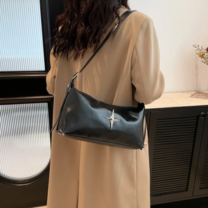 Minimalist black glossy underarm bag with silver star buckle worn with a khaki blazer