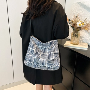 Blue and white geometric pattern canvas tote bag with black strap on model