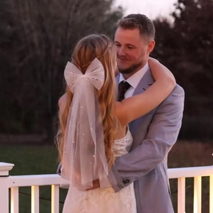 Close-up of romantic white tulle hair bow with pearls on a bride in a sunset wedding scene