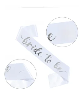 Detail of white satin Bride to Be sash with silver lettering and fabric texture close-up
