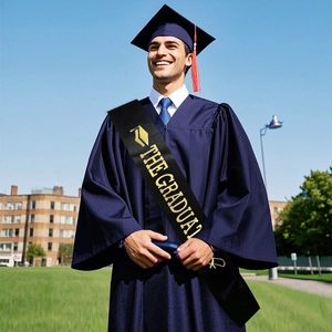 Navy blue graduation gown with cap and golden THE GRADUATE sash on campus setting