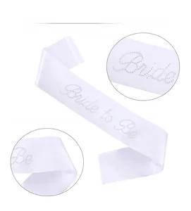 Close-up of white satin Bride to Be sash featuring sparkling rhinestone lettering