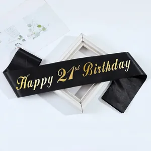 Satin black 21st birthday sash with gold lettering on a minimalist decorative background