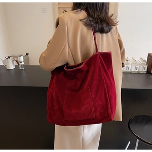 Macro view of burgundy suede tote bag featuring plush velvet texture and front pocket detail