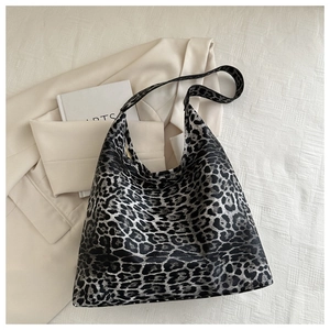 Detailed flat lay of silver leopard print tote bag on a textured fabric background