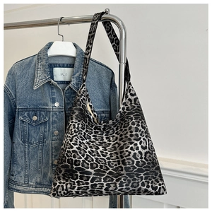 Detail of a large leopard print tote bag hanging on a rack with denim background