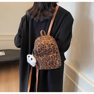 Détail d'un mini sac à dos léopard avec charm panda en peluche et fines bretelles brunes