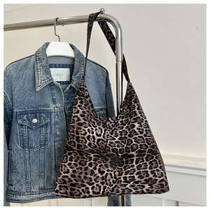 Detail of high-capacity leopard print hobo shoulder bag hanging on a metal hanger