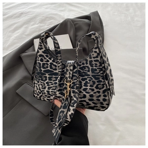 Détail du sac hobo à imprimé léopard avec ferrures dorées et bandoulière sur une veste