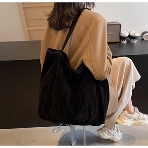 Detail of minimalist black oversized tote bag with functional exterior square pocket
