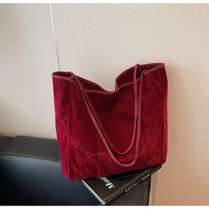 Detail of burgundy faux suede tote bag with front pocket shown in a lifestyle scene
