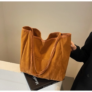 Detail shot of the suede tote bag in tan featuring an outer pocket and slender strap