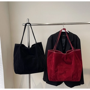 Detail view of large velvet tote bags in black and burgundy with front patch pockets