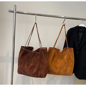 Detail of minimalist suede tote bags in dark brown and mustard colors with front pocket